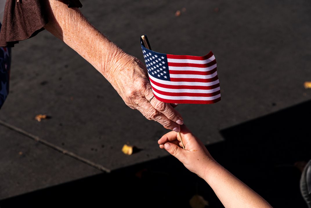 two hands pass an American flag
