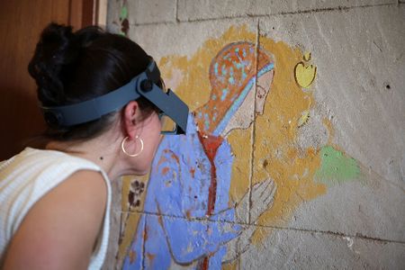 A conservator examines an illustration hidden beneath a mural by Odilon Redon.