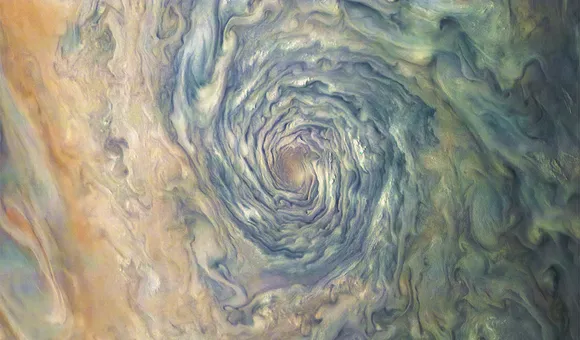 A massive atmospheric vortex on Jupiter is a dizzying swirl of brown, yellow, and green clouds that form a deep tunnel.