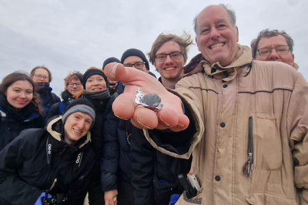 Researchers pose with a fragment of asteroid 2024 BX1 they found in Germany. The rock is a very rare type of meteorite called an aubrite.
