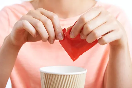 A woman adds artificial sweetener to a drink. The paranoia over the health dangers of aspartame can be traced back to an early Internet hoax.