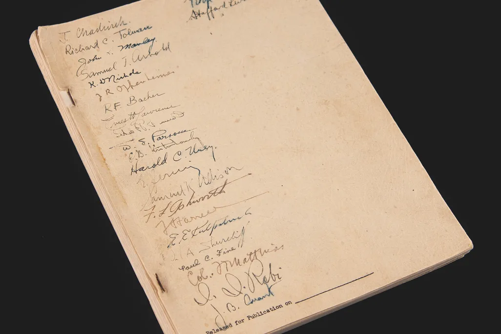 Piece of paper with lots of signatures against black background