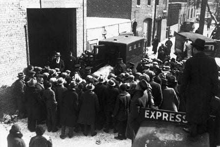 Onlookers watch as police remove the bodies of the victims of an execution-style murder from the scene at 2122 North Clark Street in Chicago. 