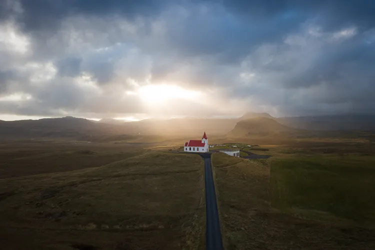 OPENER - A church with a red roof and steeple sticks out against the sprawling landscape as the sun pokes through the hazy clouds.