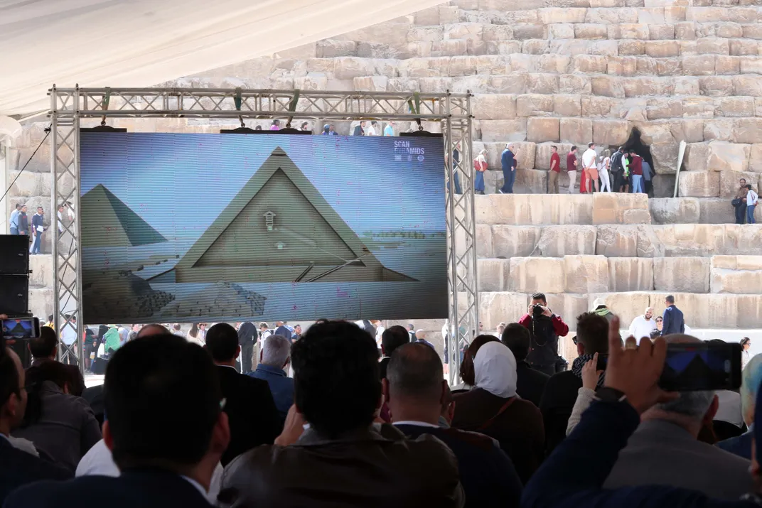 People attending a press conference viewing a screen