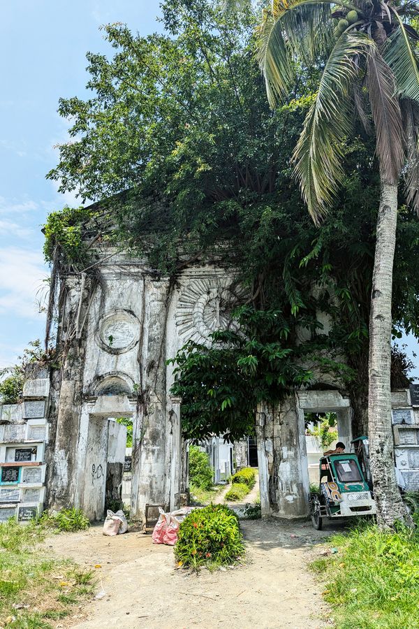 A man in motorized tricycle waits outside a cemetery in Roxas City, Philippines thumbnail