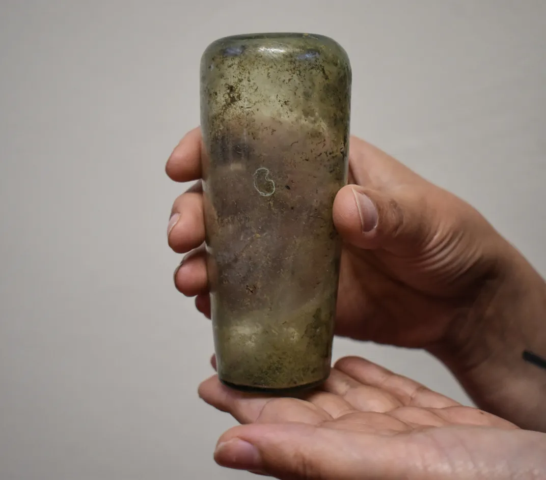A person's hands holding up a glass vessel