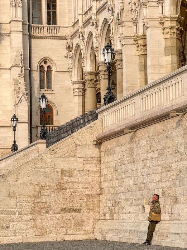 Man resting on a wall of the House of Parliament in Budapest, Hungary thumbnail