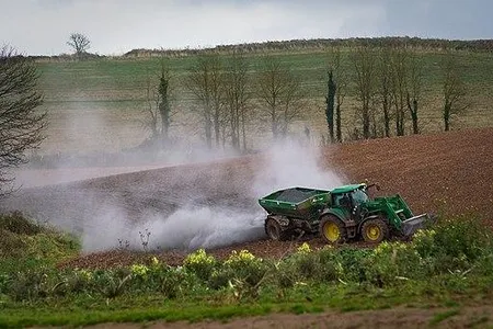 A farmer distributes lime over a field in the UK. A new climate solution would use a similar technique to spread rock dust. 