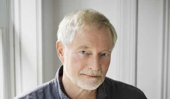 A portrait of a man wearing a dark shirt