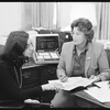 Gail Winslow sits at a desk reviewing documents with another woman.