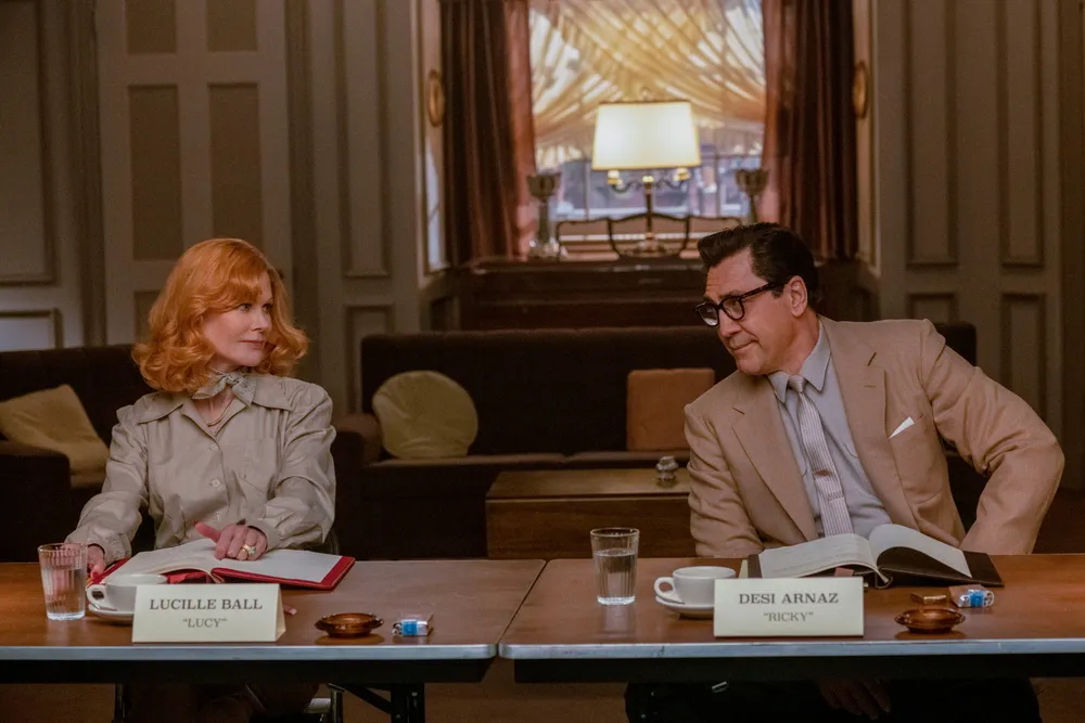 Nicole Kidman as Lucille Ball and Javier Bardem as Desi Arnaz sitting at a table