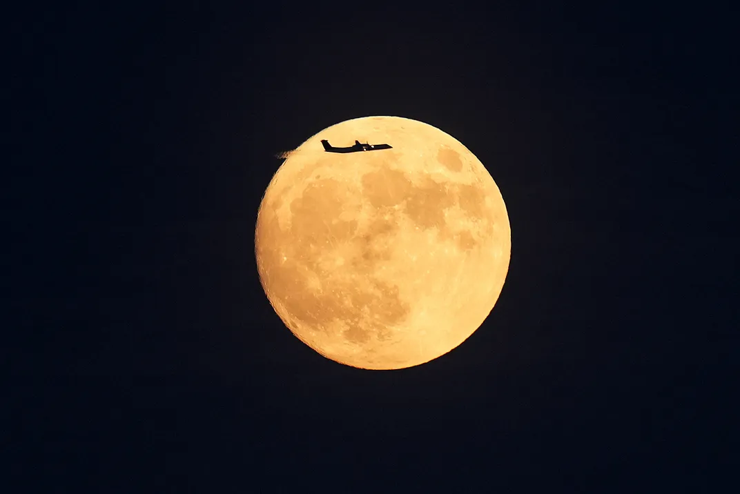 Airplane flies in front of the full strawberry moon in Toronto
