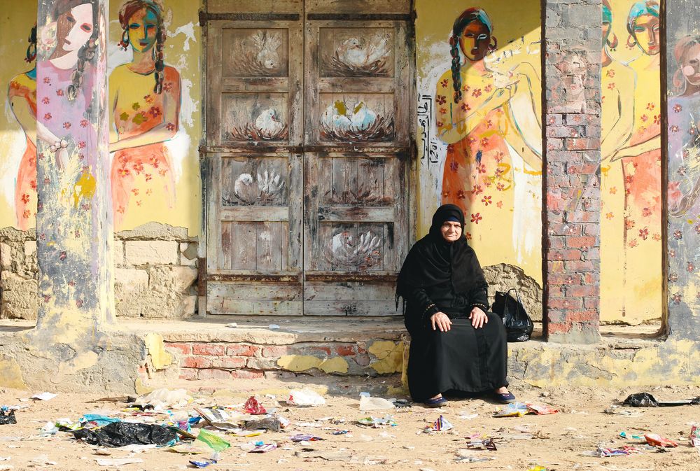 A woman sitting in the area of the colorful houses in Kafr El-Sheikh.