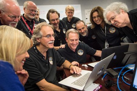 Members of the New Horizons team and journalists review new processed images from the New Horizons spacecraft, July 15, 2015. (Embedded journalist, standing left, Jeff Moore, science team, NASA Ames Research Center; Randy Gladstone science team Southwest Research Institute (SwRI); Andy Chaikin, science writer; Willam Lewis, science writer; Will Grundy, science team, Lowell Observatory; Maria Stothoff, media relations, Johns Hopkins University Applied Physics Laboratory (APL); Steve Maran, science writer. Seated; Laura Cantillo, NASA media relations, left, John Spencer, science team, Southwest Research Institute; and New Horizons Principal Investigator Alan Stern of SwRI.)