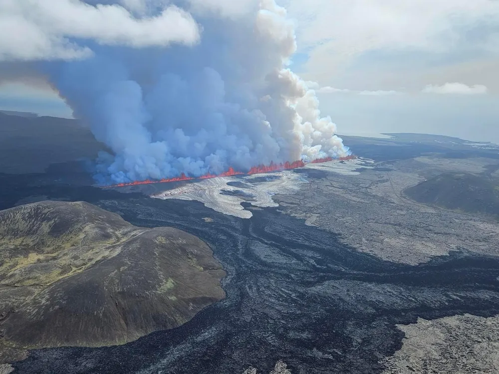 Aerial photo of lava and spurting from the ground and smoke rising above it