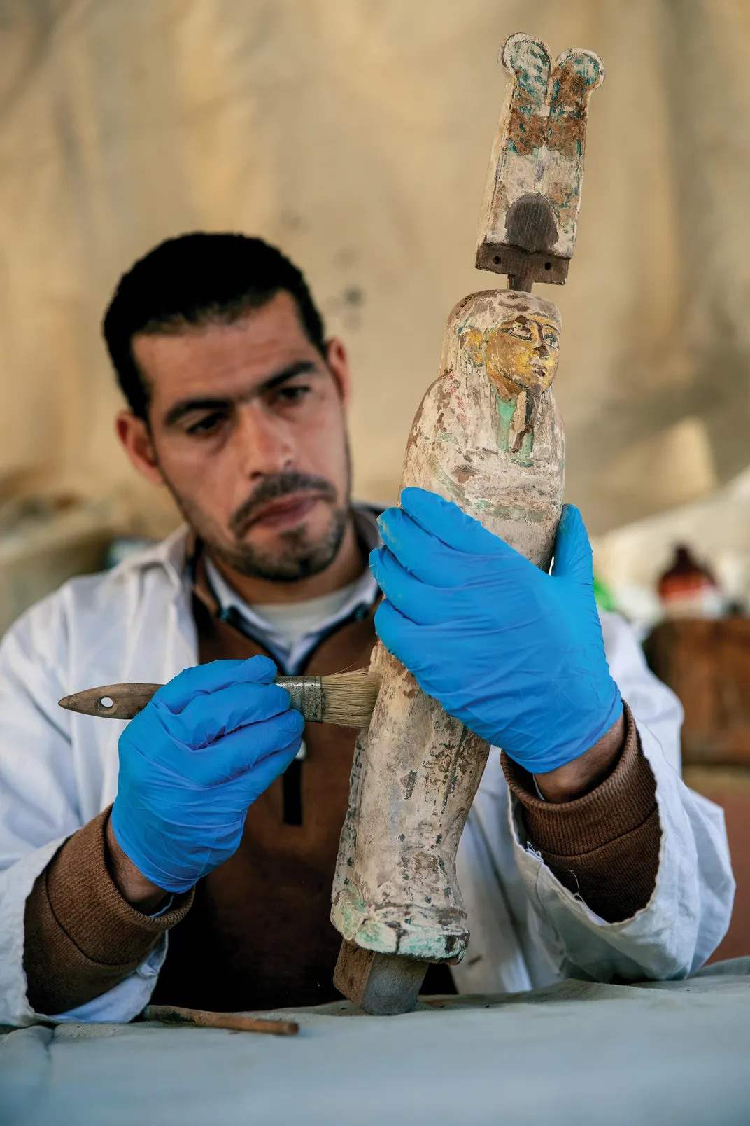 A conservator cleans a statuette