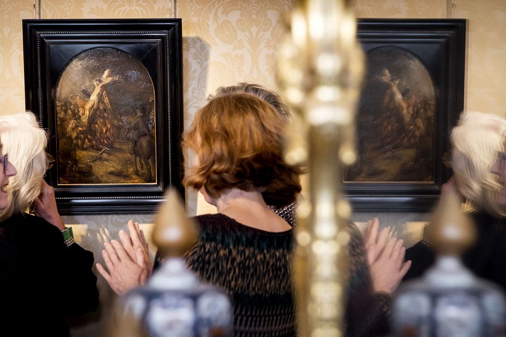 Visitors are reflected in a mirror as they look at The Creation of Jesus on the Cross by Rembrandt on display at Museum Bredius in The Hague on November 3, 2022.