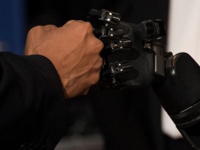 President Barack Obama fist bumps a robotic arm being controlled by electrodes implanted in Nathan Copeland's brain at the University of Pittsburgh on October 13, 2016.