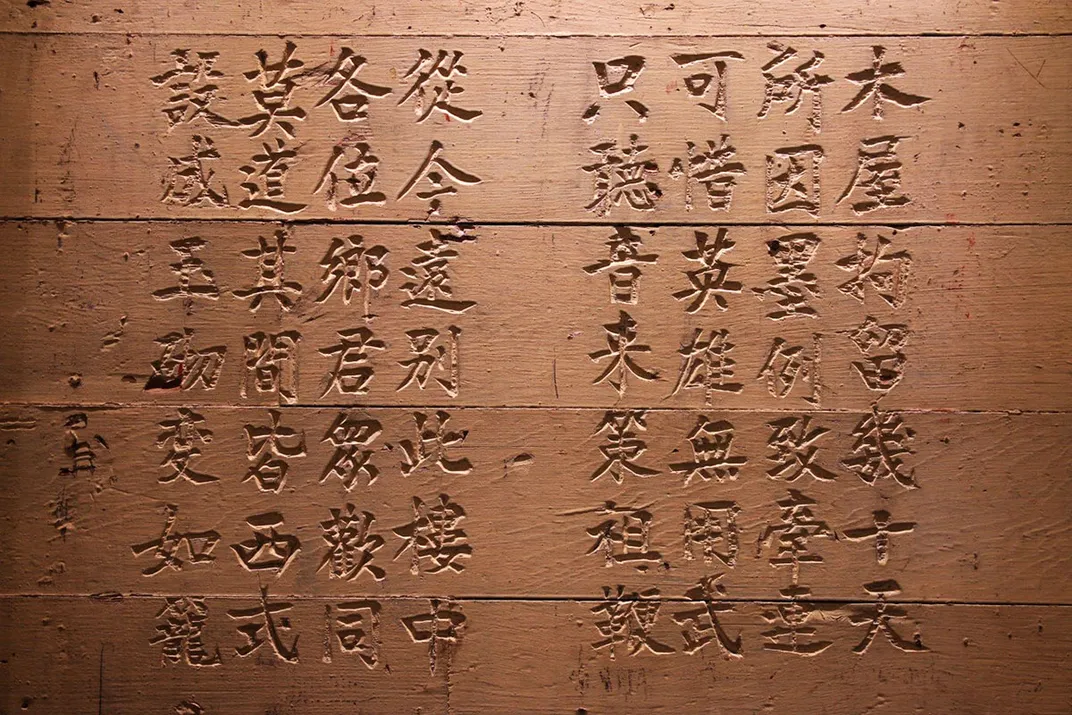 Brown stone wall etched with Chinese characters.