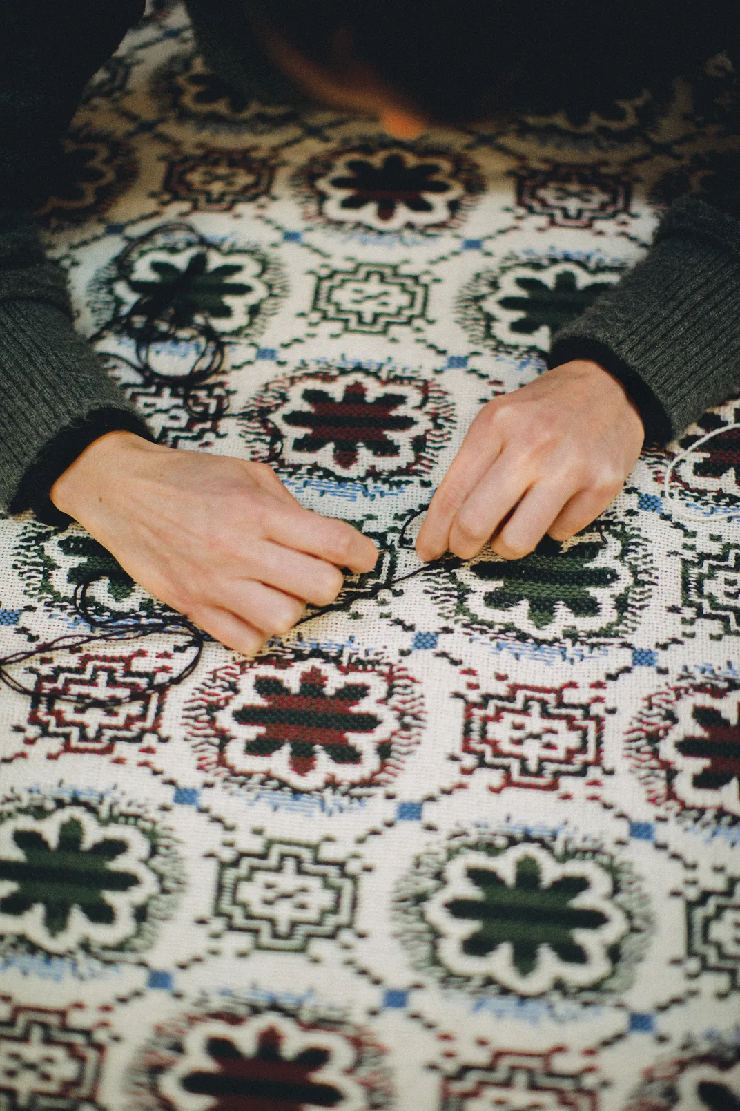 a close up of hands fixing a newly made textile