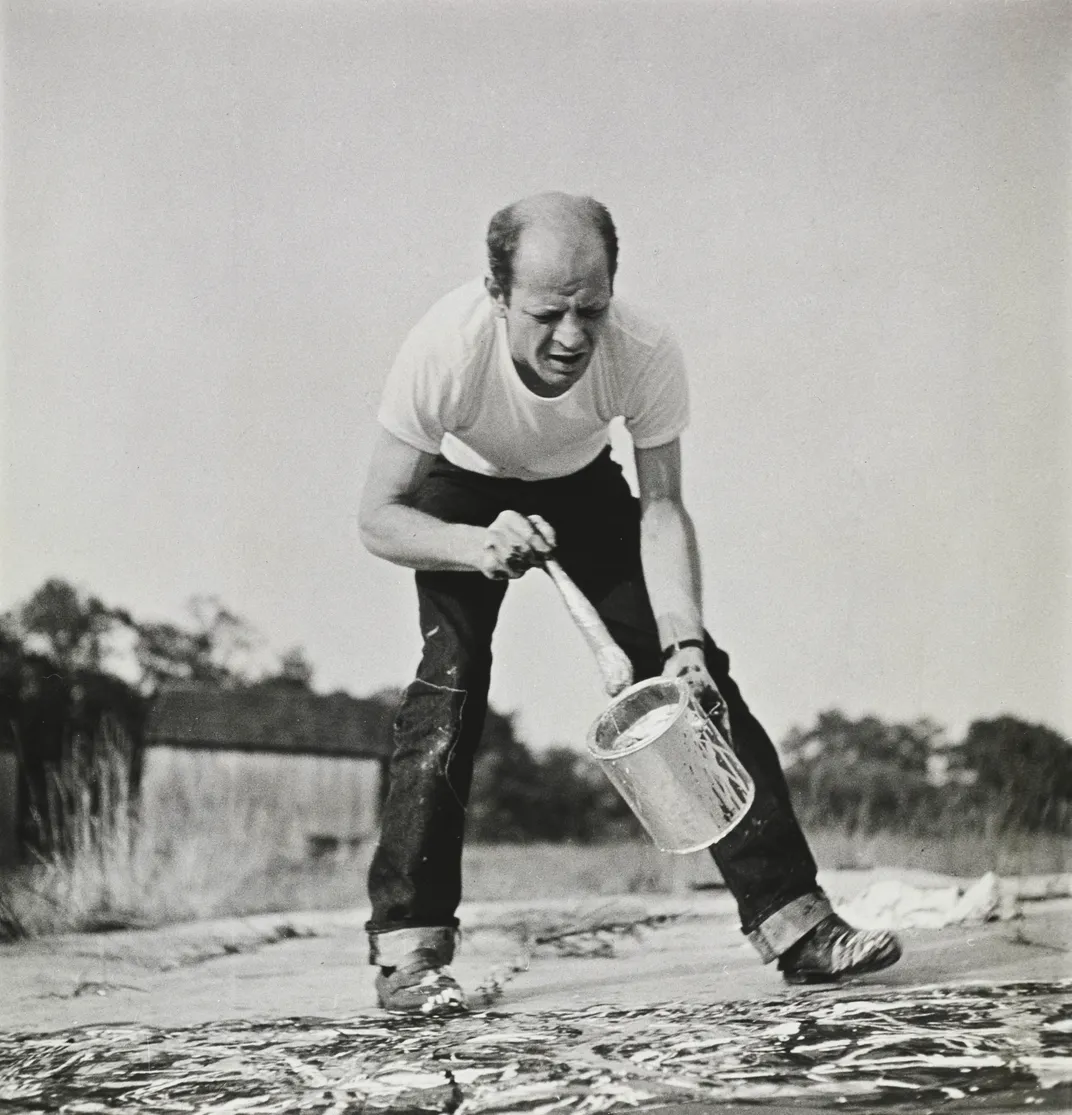Jackson Pollock standing over a canvas