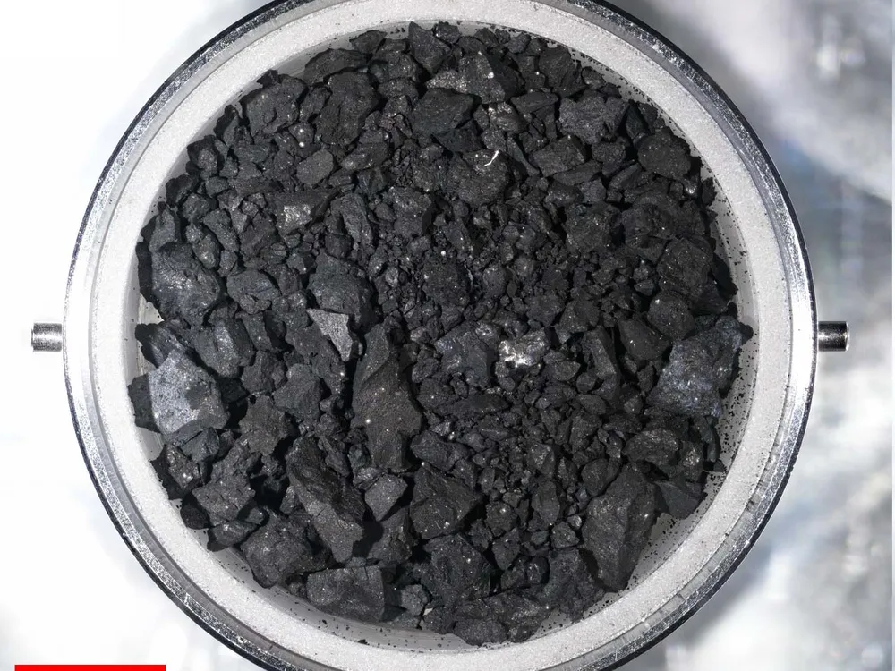 An image of black rocky like material in a small metal dish. The sample is material from the surface of Asteroid Ryugu.