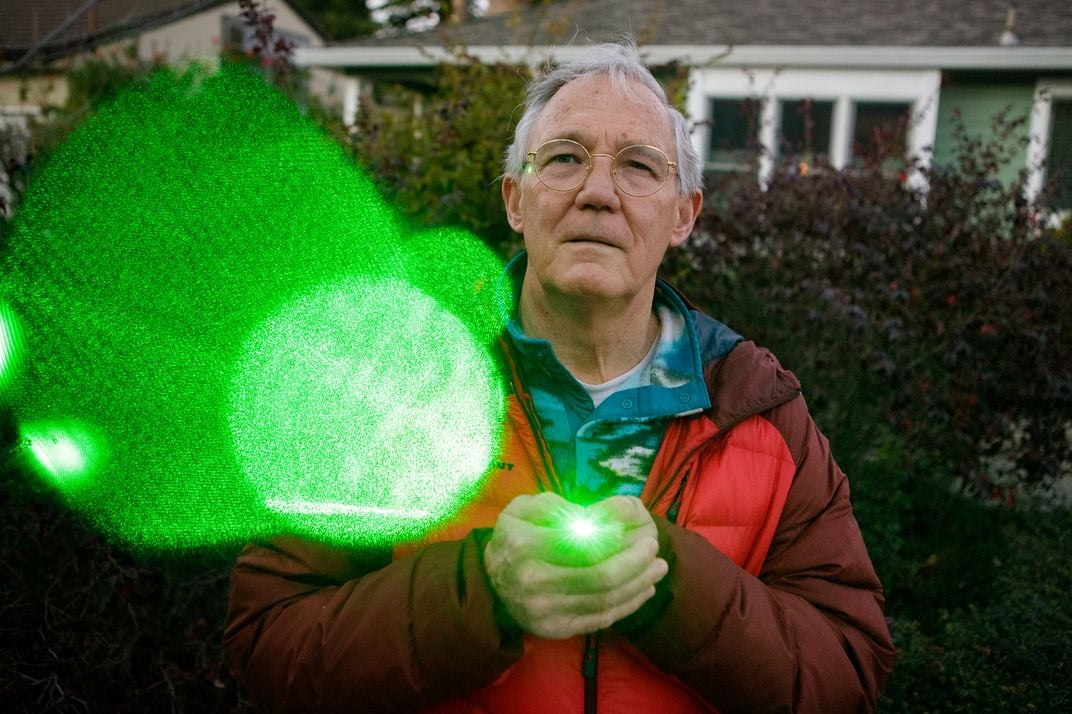 A man holds a green laser
