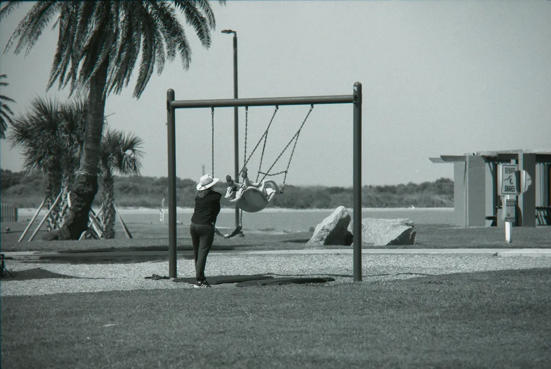 A person pushes a child on a swing at Seawolf Park in Galveston