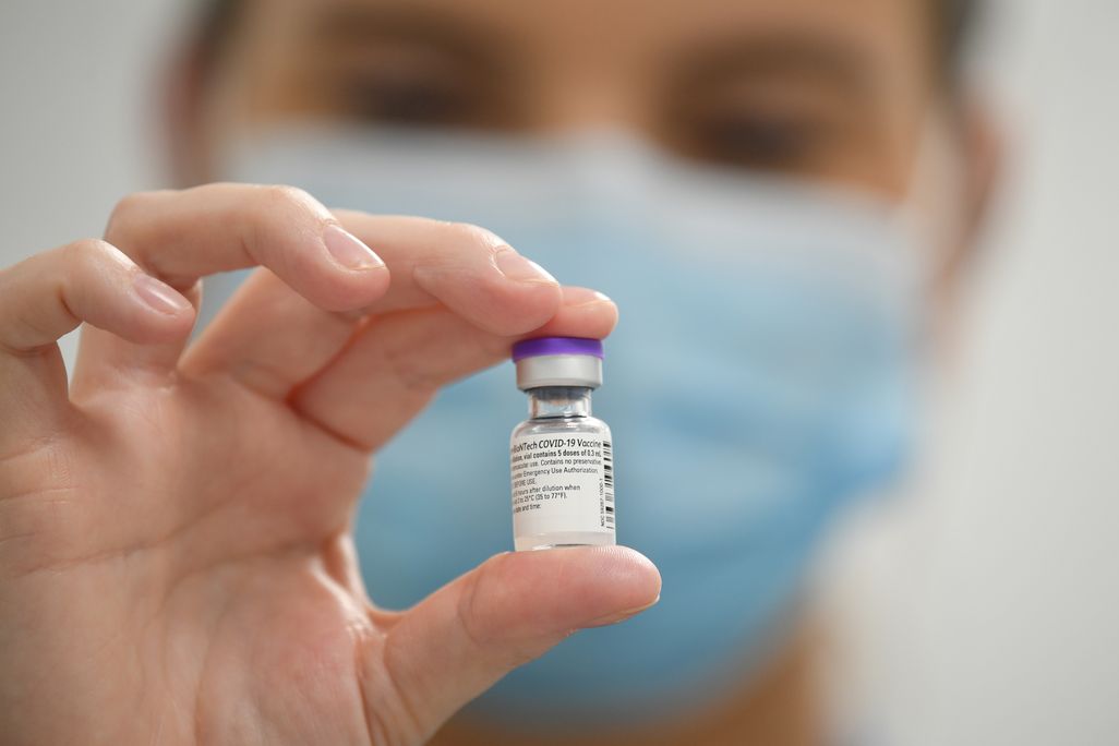 a doctor holds a vial of the Pfizer covid vaccine toward the camera
