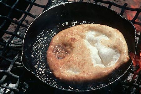 Navajo frybread cooks in an iron frying pan.