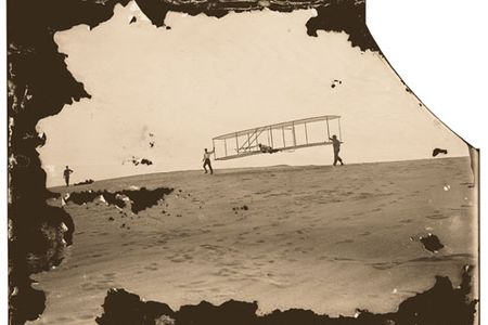 Day after day, the brothers (Wilbur, left, and Orville at the controls) put their new and improved glider through its paces. Assistant Dan Tate lent a hand.