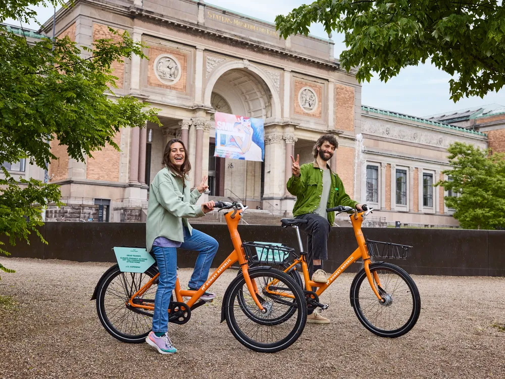 A woman and a man posing for a photo astride bikes
