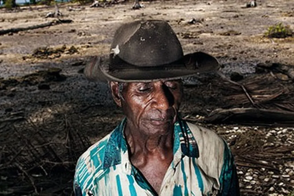 Posakei Pongap, a Manus islander, in front of a field ruined by salinization.