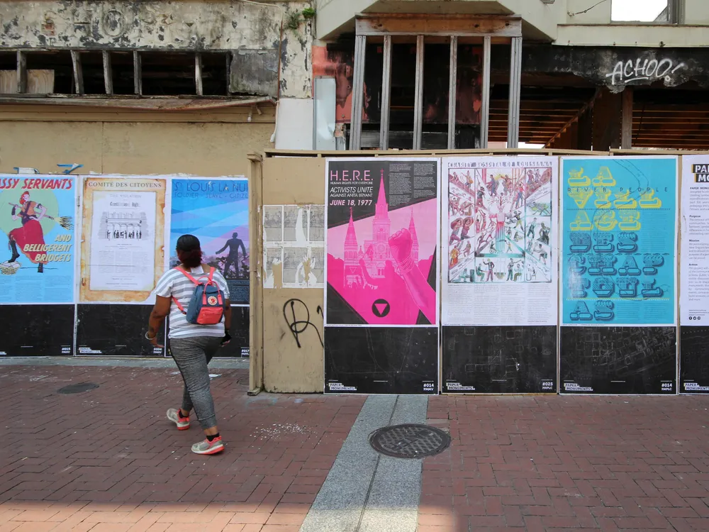 A person looking at a wall of posters in front of a building under construction