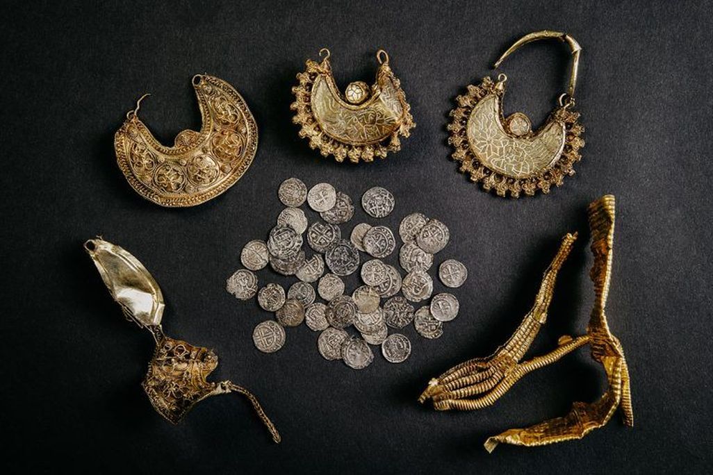 Black background with gold earrings, silver coins and gold leaf