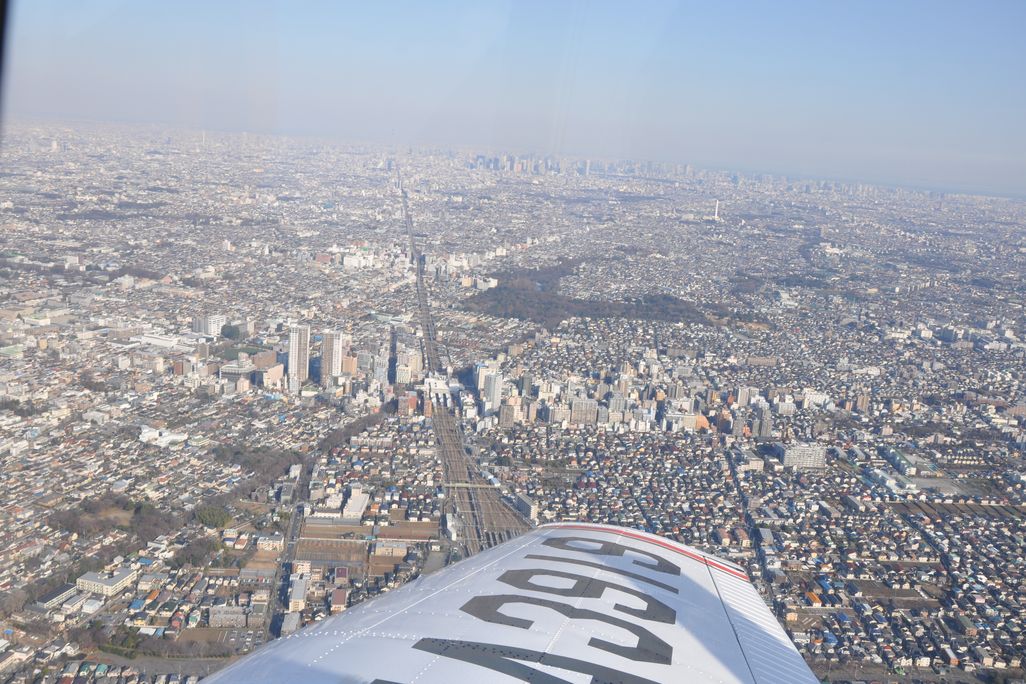 view out an airplane window with the wing in the foreground and a city in the background