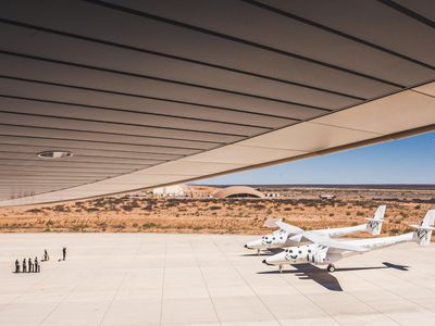 Outside Spaceport America’s hangar surrounded by the New Mexico desert, a ground crew salutes Virgin Galactic’s WhiteKnightTwo carrier ship. The aircraft, VMS Eve, flew in last August from its original home in Mojave, California.