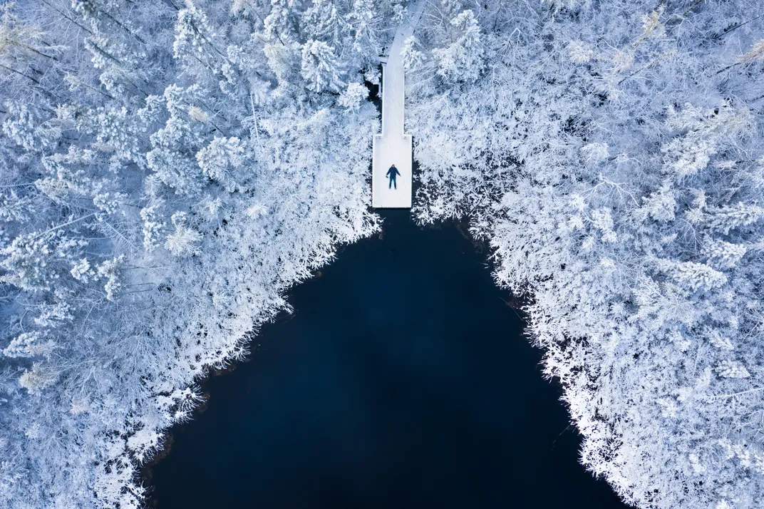 a person laying on a snow covered dock is shown from above