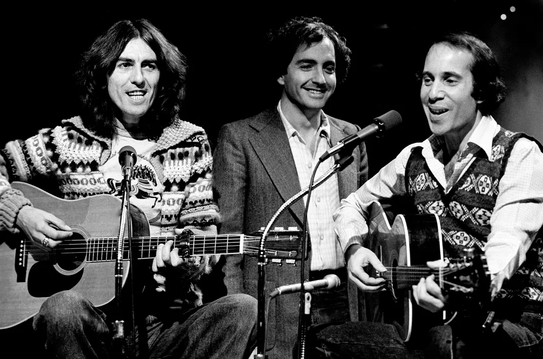 George Harrison (left) and Paul Simon (right) record songs for "Saturday Night Live" on November 19, 1976, with Lorne Michaels (center) looking on