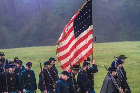 Soldiers on the Union side look solemn as they carry a large flag.