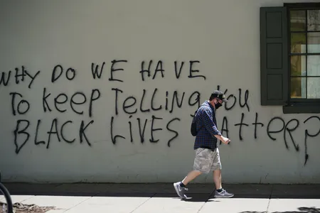 A man passes by graffiti on the side of the slave quarters of Decatur House in Washington, D.C. 