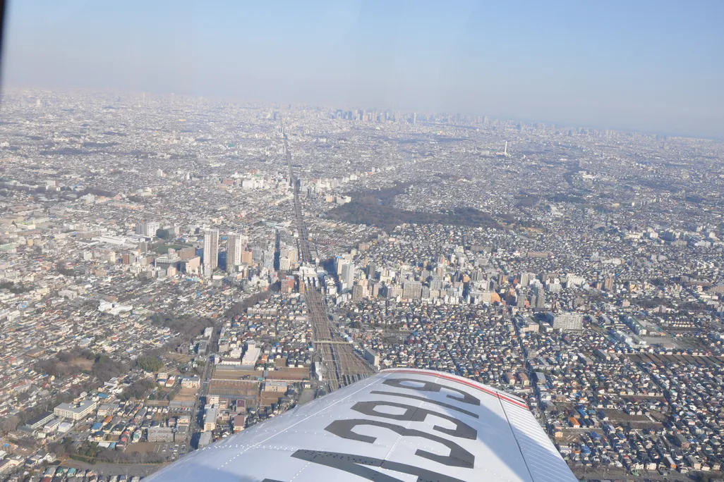 view out an airplane window with the wing in the foreground and a city in the background