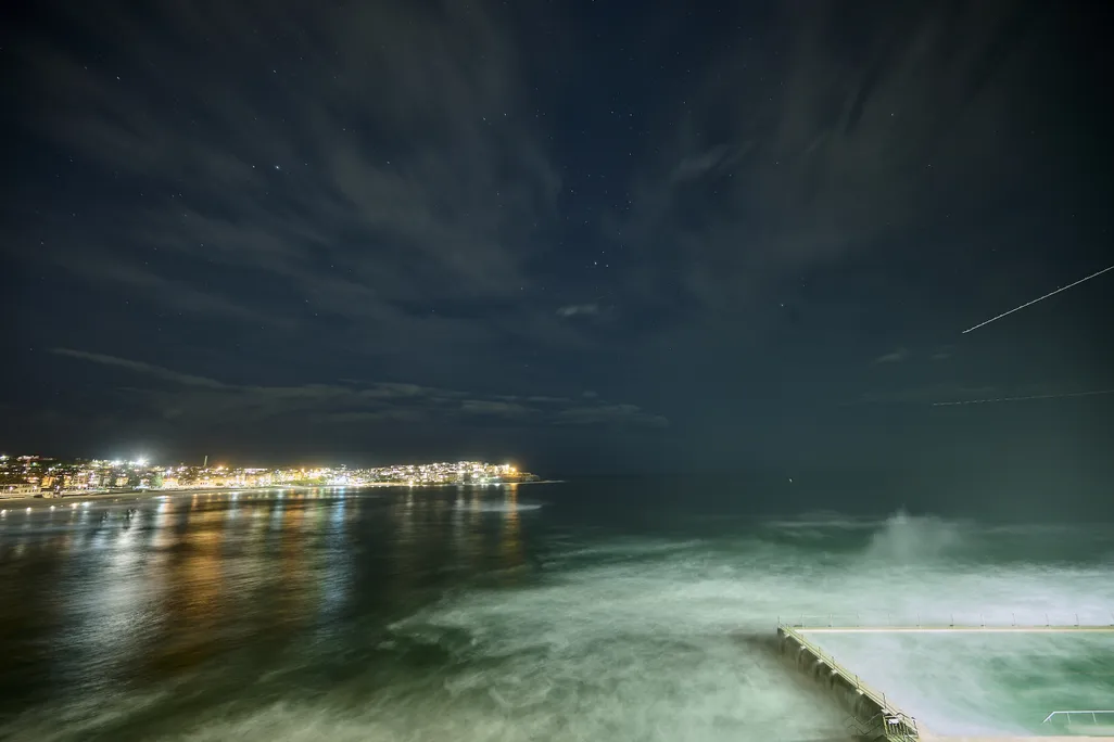 Meteor streaking across the sky with city lights in the background