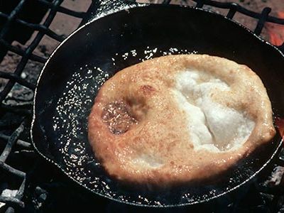Navajo frybread cooks in an iron frying pan.
