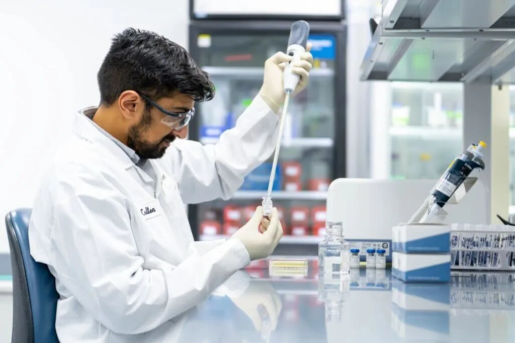 a lab technician uses a long syringe type instrument over a recombinant Cascade Reagent cartridge