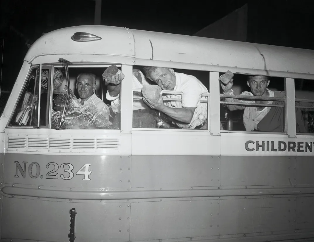 Concertgoers hold up rocks thrown at their bus by rioters.