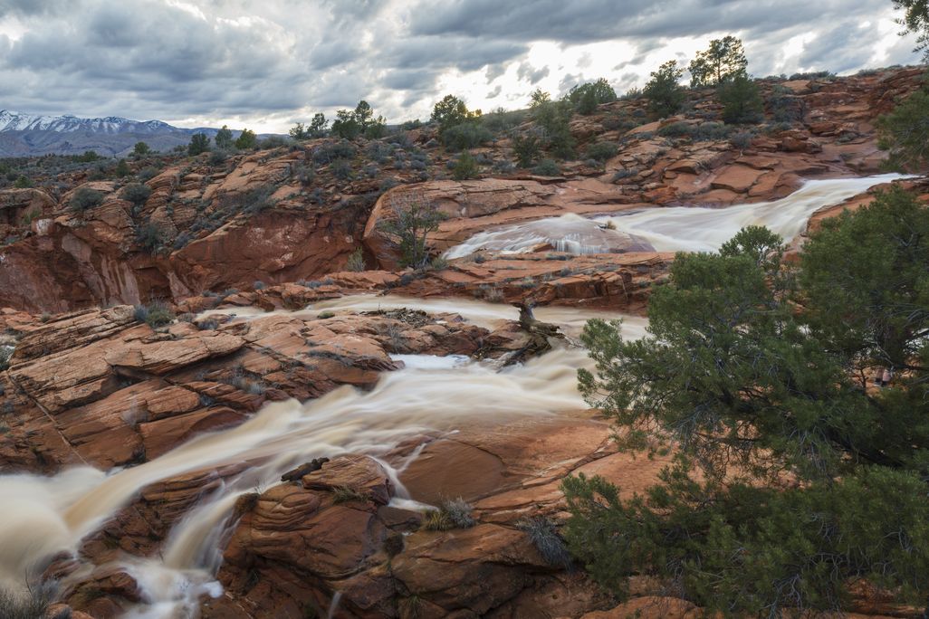 Waterfall spilling over red rocks with trees surrounding