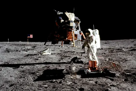 Apollo 11 astronaut Buzz Aldrin works at the deployed Passive Seismic Experiment Package on July 20, 1969. To the left of the United States flag in the background is the lunar surface television camera.

