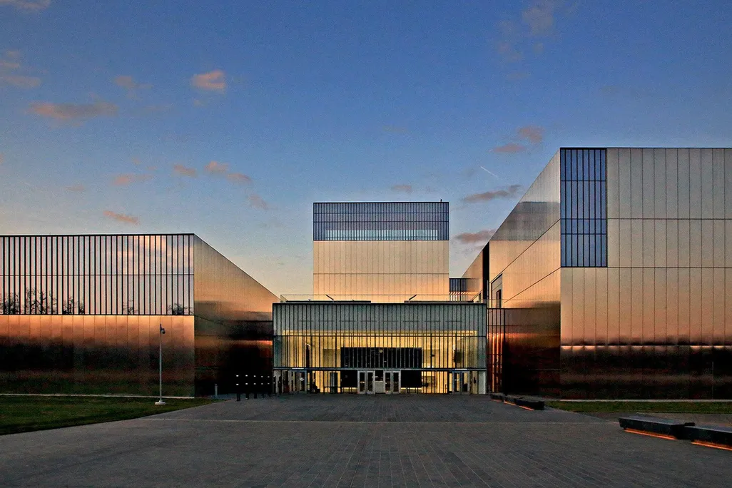 An image of a large, boxy museum with a facade of polished stainless steel and rectangular windows; very modern